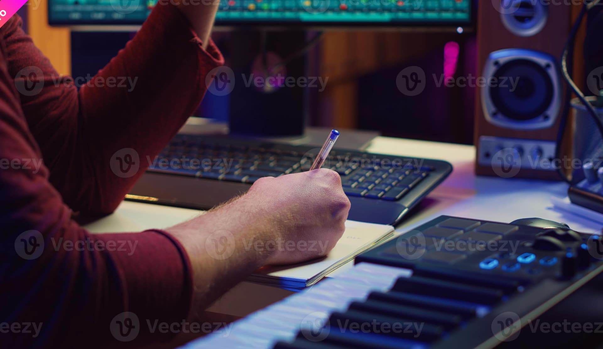 A hand writing notes next to a music keyboard
